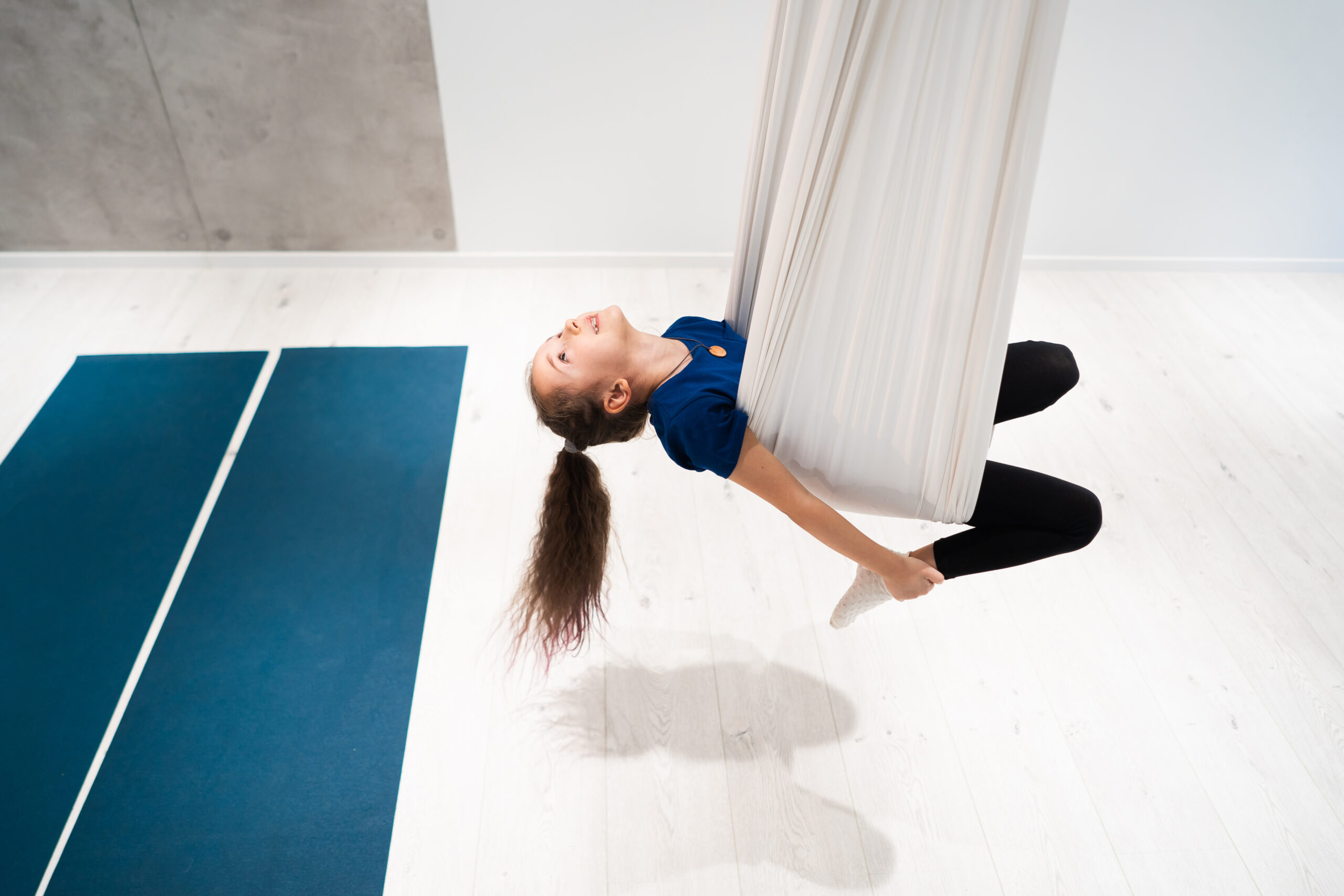 portrait of a beautiful young girl engaged in fly yoga on canvases.